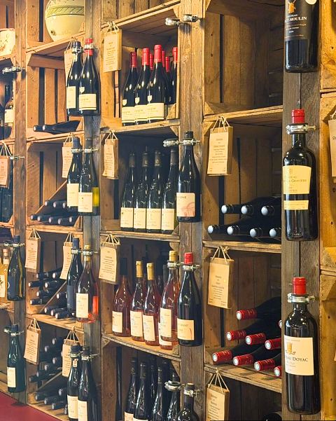 Weinregal aus Holzkisten mit Rotweinen und Schildern